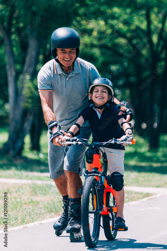 Obraz premium Grandfather and grandson have fun roller skating and biking