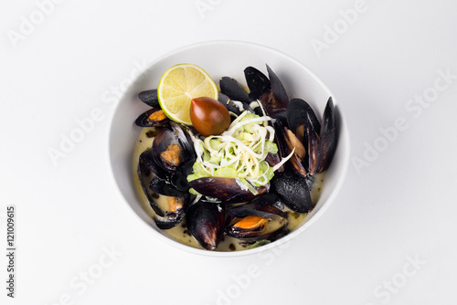 Blue mussels in a creamy sauce with lemon and olive in white bow photo