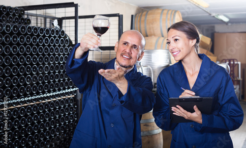 man and woman winemakers in wine cellar .