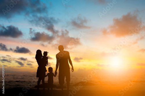 Silhouette family mother, father and young son holding hands, ta