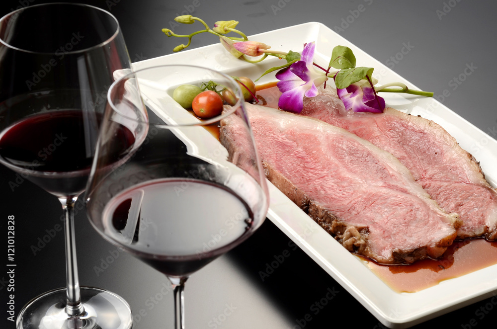 Fresh roasted beef with glass of red wine on white plate with he