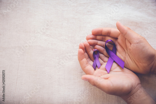Hands holding Purple ribbons, Alzheimer's, Epilepsy, world cancer day, domestic violence awareness concept