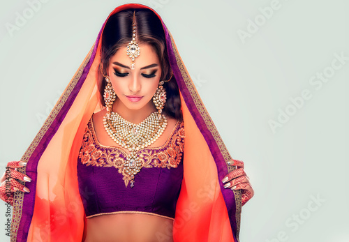 Portrait of beautiful indian girl . Young hindu woman model  with tatoo mehndi  and kundan jewelry . Traditional Indian costume lehenga choli .
 photo
