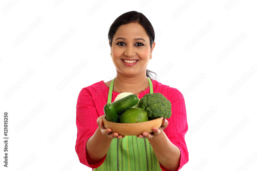 Smiling female chef holding bowl full of vegetables and fruits Smiling female chef holding bowl full of vegetables and fruits
