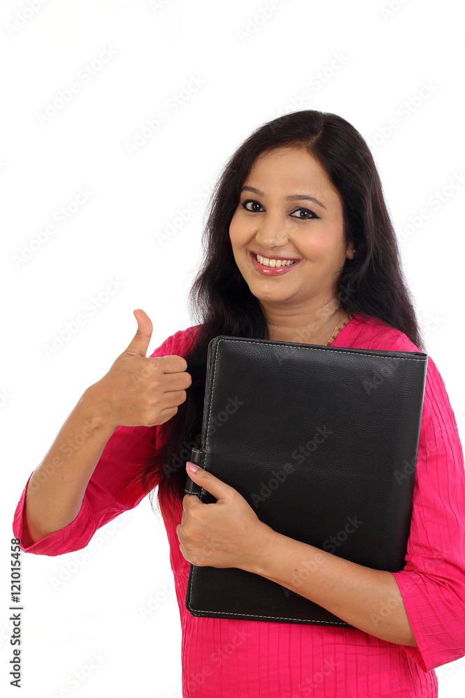 Happy female student holding folder and making thumb up gesture Happy female student holding folder and making thumb up gesture
