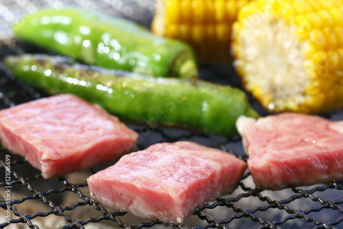 Grilling cubed pork meat with green chili and corn on hot charco