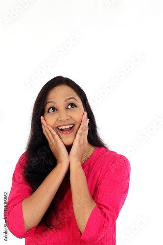 Surprised young woman looking up against white background