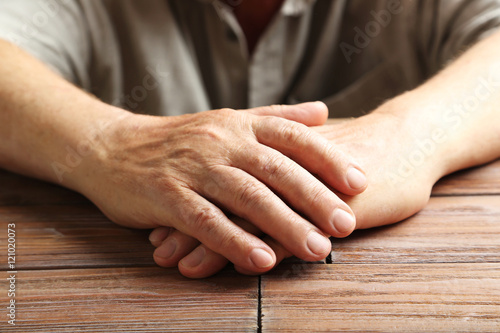 Hands of old senior on a wooden table