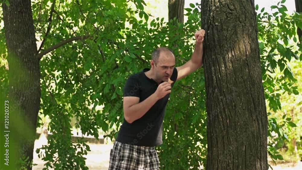 Young man eating ice cream near a tree in the Park Young man eating ice cream near a tree in the Park
