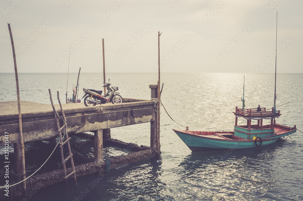 motorcycle and local fisher boat at pier.