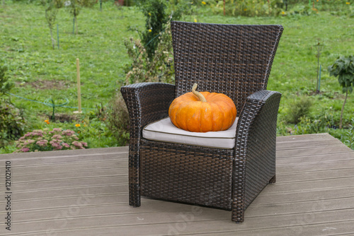 Mr. Pumpkin on the on a wicker chair, preparing for Halloween