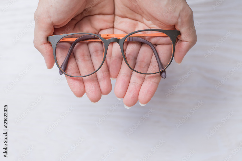 Close up cleaning glasses by microfiber cloth for cleaning lens and glasses concept.Close up cleaning glasses by microfiber cloth on white wood table. Close up cleaning glasses by microfiber cloth for cleaning lens and glasses concept.Close up cleaning glasses by microfiber cloth on white wood table.