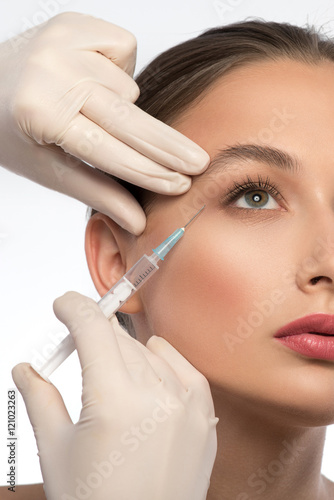 Experienced beautician injecting woman face