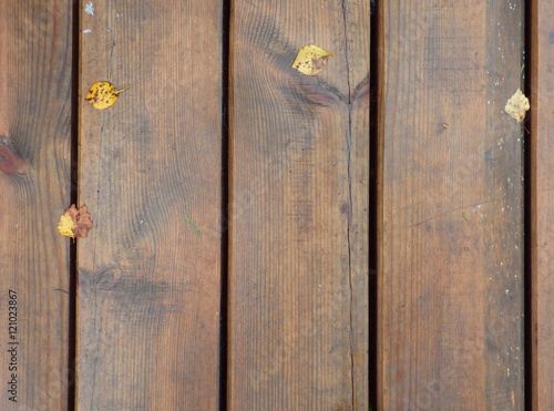 Fotografie Some fallen leaves on brown wooden texture