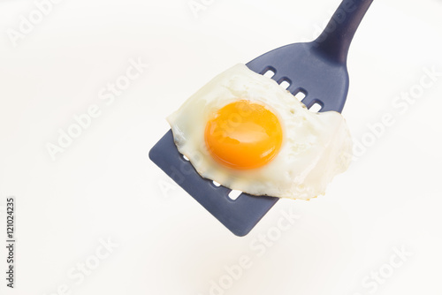 Appetizing and Perfectly Fried Egg on a Spatula, isolated on white background