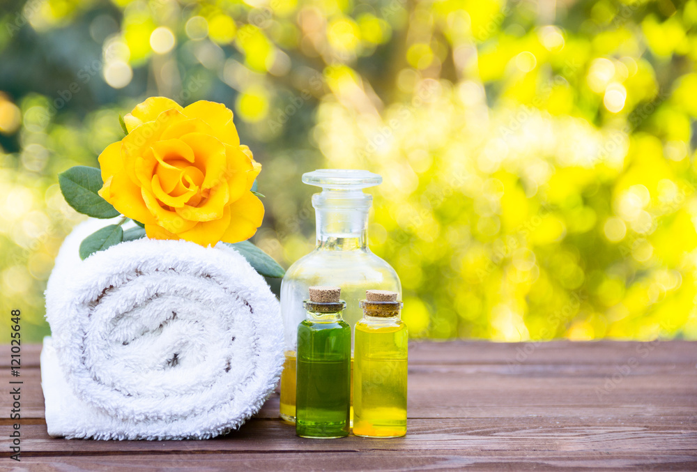 Massage oil, white towel and flower elixirs. Cosmetics for saunas and spa treatments. Spa concept. Essential oils. Cosmetics for saunas and spa treatments. Fragrant yellow rose. Copy space. 