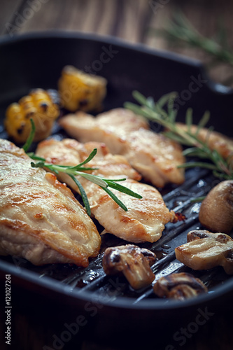 Grilled chicken breast with mushroom and rosemary on a wooden board or grill pan 