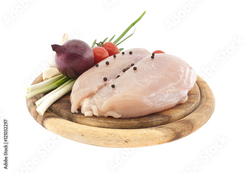 Raw chicken breasts on wooden cutting board with vegetable