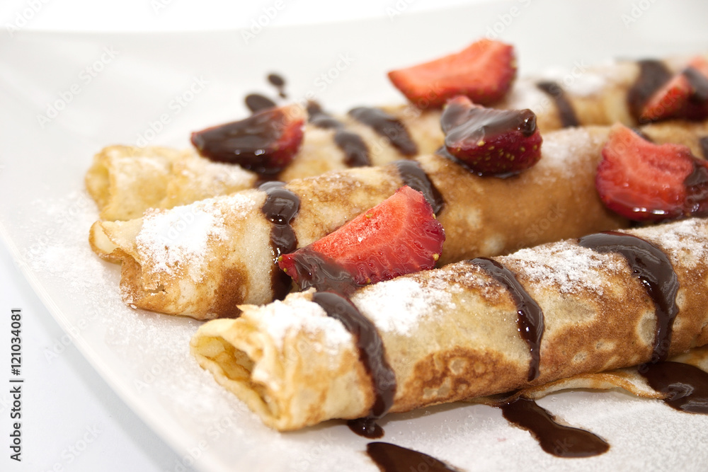 Sweet dessert of rolled pancakes on a plate with strawberry Sweet dessert of rolled pancakes on a plate with strawberry