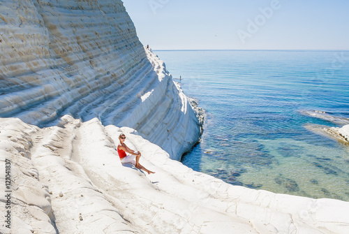 Foto A girl sits on a slope of white cliff called Scala dei Turchi