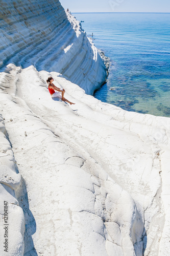 Bild auf Leinwand A girl sits on a slope of white cliff called Scala dei Turchi