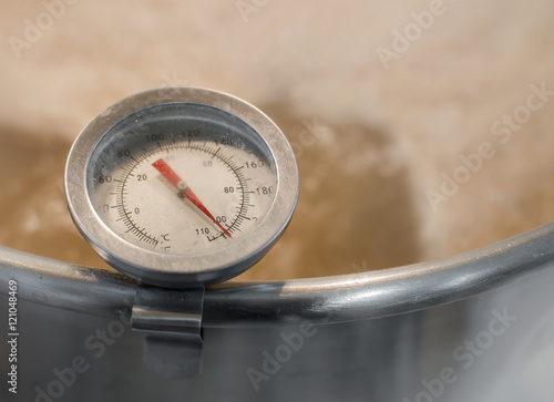 Stainless steel kitchen thermometer measures the temperature of boiling wort beer homebrew ( warm tone color ).