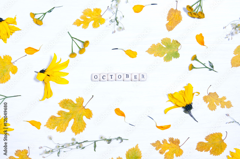 The word october on the background of yellow flowers and leaves