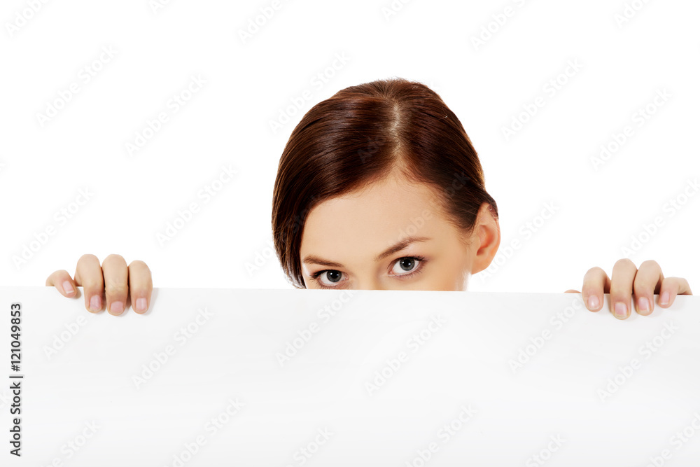 Beautiful student woman hiding her face behind blank banner Beautiful student woman hiding her face behind blank banner