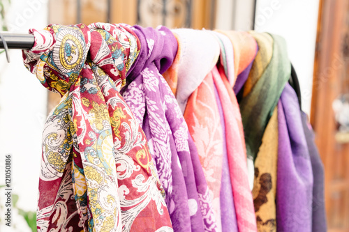 Colorful scarves hanging on metal bar