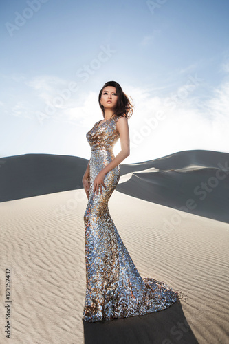 Fashion asian woman model in luxury shiny dress in desert