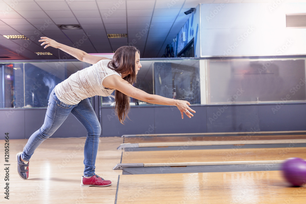 young girl pulls the ball on the bowling alley
