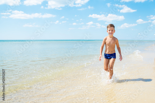 Cute little boy running through the water at beach © alexytrener