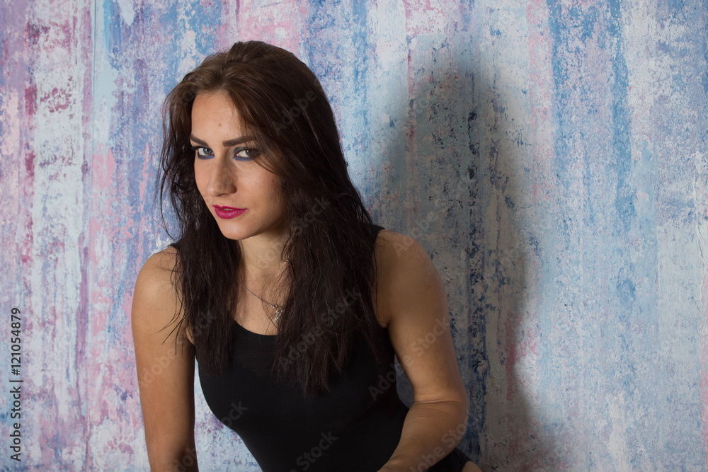 Fototapeta premium Девушка сексуальная в пиджаке и купальнике на кушетке на фоне кирпичной серой стены