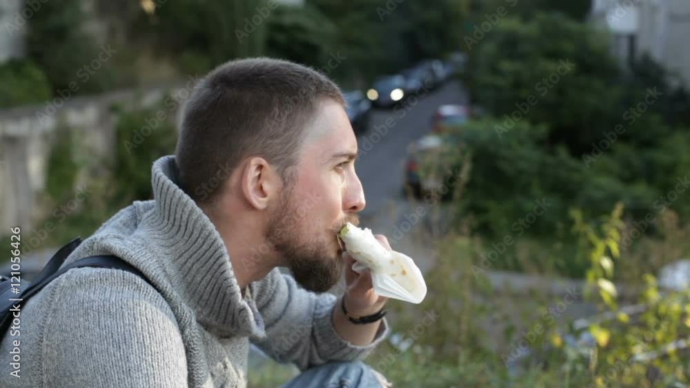 Close up young man eating kebab and drinking coffee outdoors Close up young man eating kebab and drinking coffee outdoors