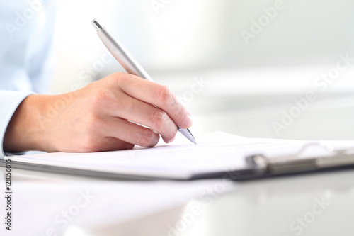 Foto Woman's hands writing on sheet of paper in a clipboard and a pen