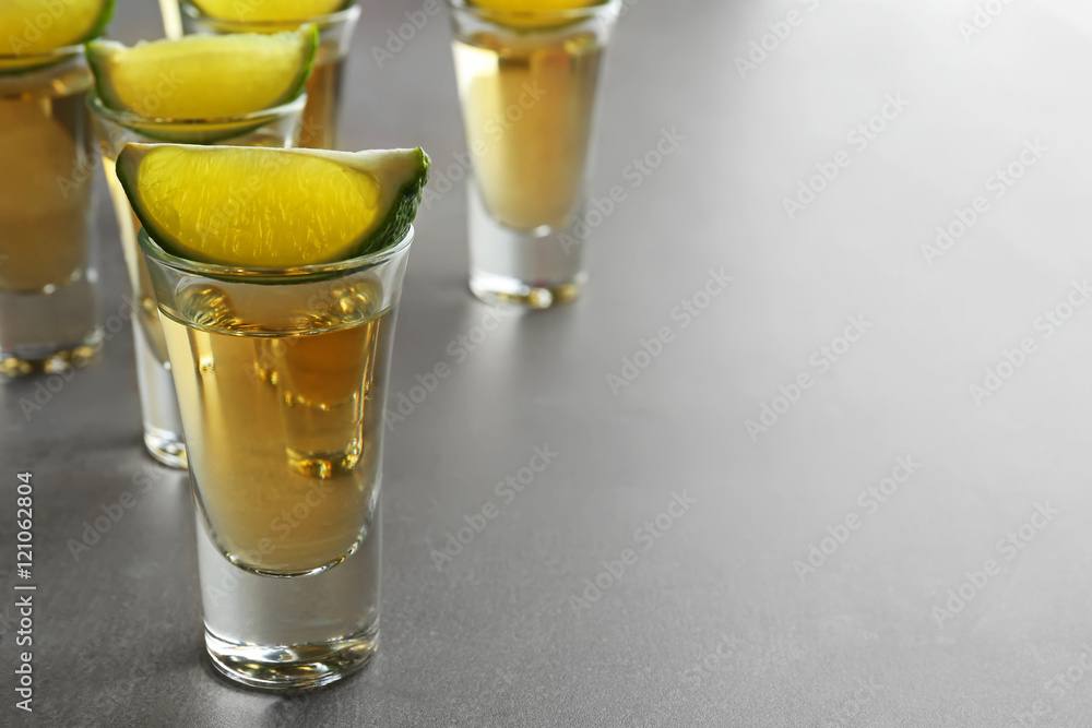 Shots of gold tequila with lime slices on light background Shots of gold tequila with lime slices on light background