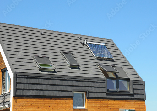 Solar panel and solar water heater on the modern house roof with skylights and dormer outdoor for energy efficiency.