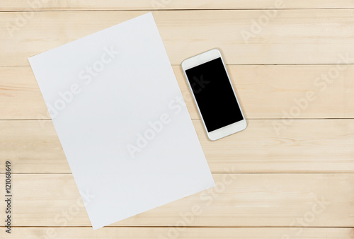 Blank paper and mobile phone on wooden panel background