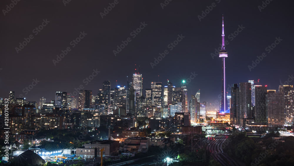 Fototapeta premium Urban lighted landscape of Toronto. A balcony view of lighted streets, parks, buildings and office towers on a hot & humid August night in capitol of Ontario, Canada.
