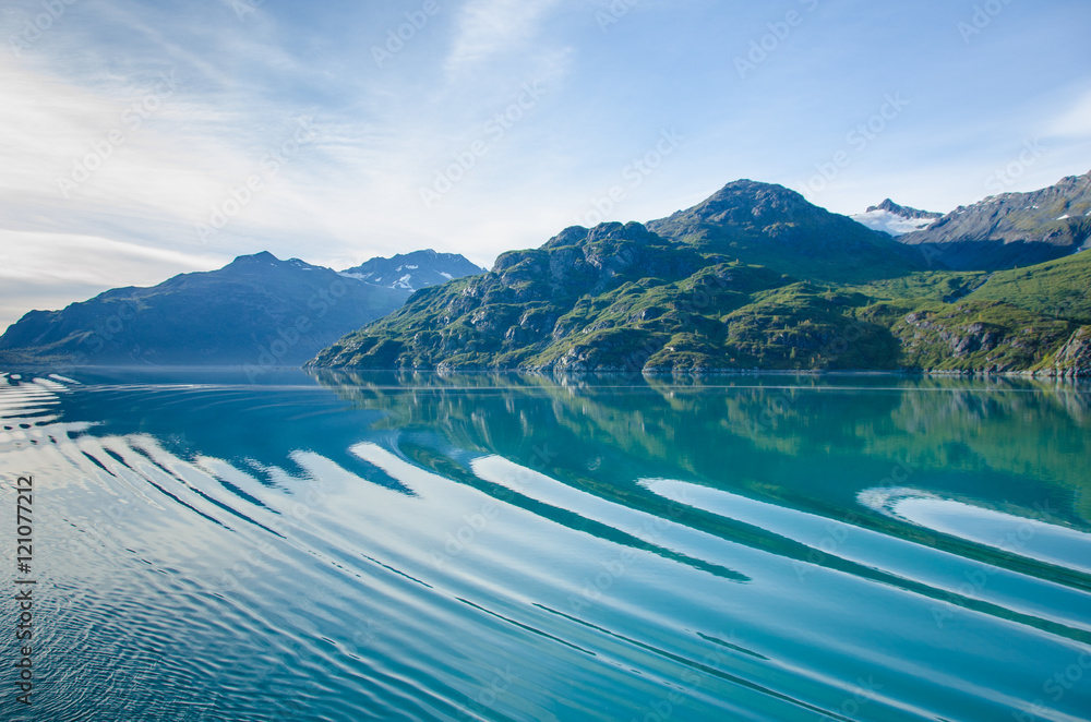 Cruise ship sailing in Southeast Alaska creates ripples across the calm waters of the Glacier Bay National Park and Preserve.