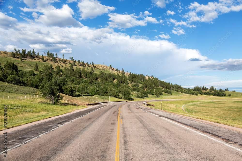 A road cuts through the hills of eastern Wyoming on a summer day. 