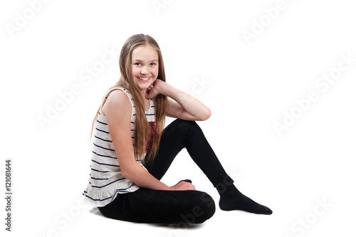 A smiling girl is sitting on floor, isolated on white background