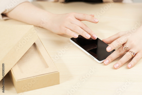 Obraz na plátně Woman using new smartphone near carton box