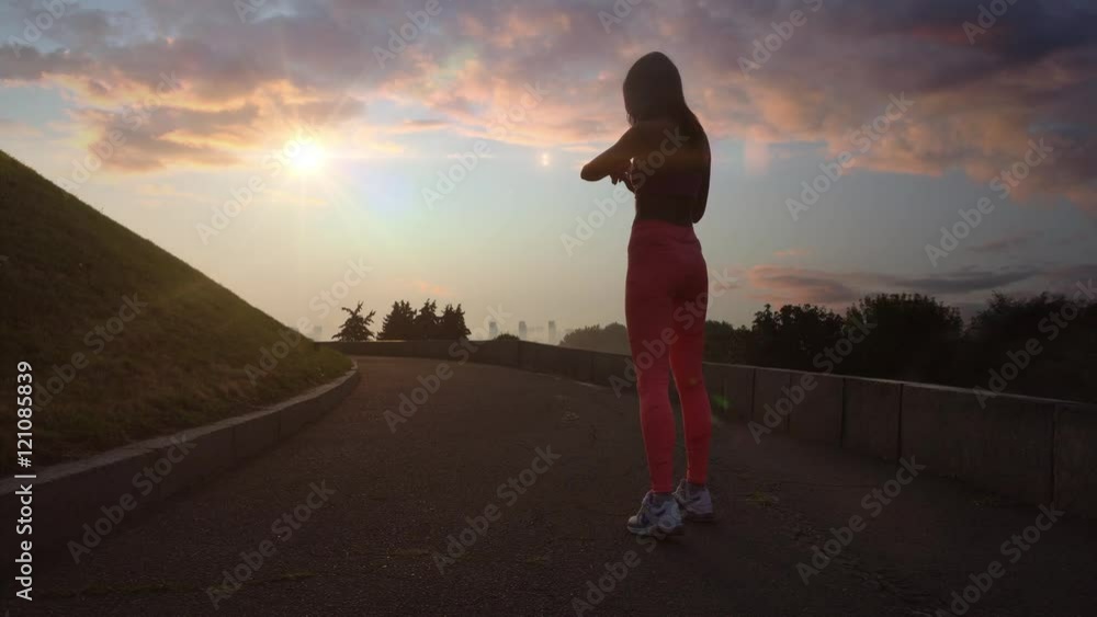 Young woman running with sportwatch in cloudy morning at sunset Young woman running with sportwatch in cloudy morning at sunset