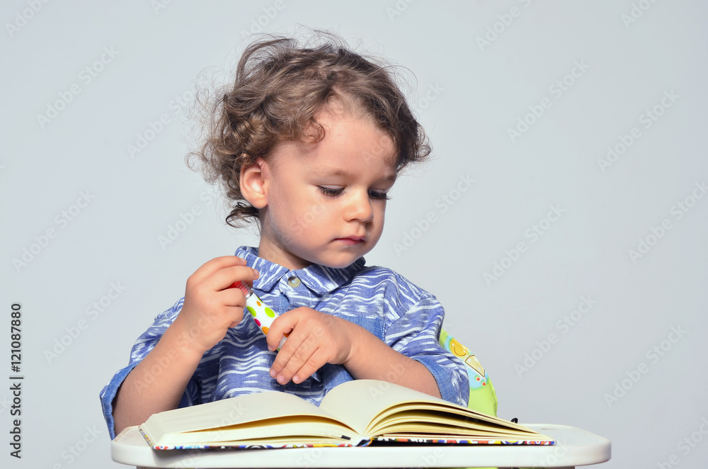 Toddler learning how to write and read. Small kid having fun preparing for school and drawing on a book. Toddler learning how to write and read. Small kid having fun preparing for school and drawing on a book.