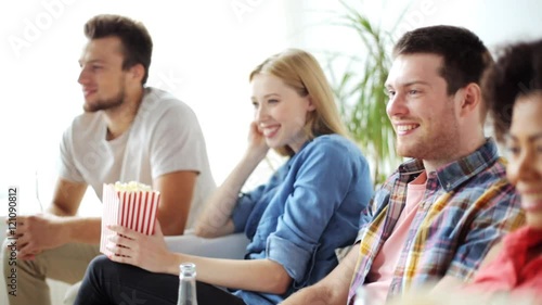 friends with popcorn and beer watching tv at home photo