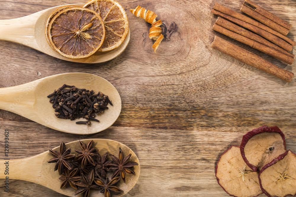 Obraz premium star anise, cloves and dried orange on wooden spoon with cinnamon and dried apple