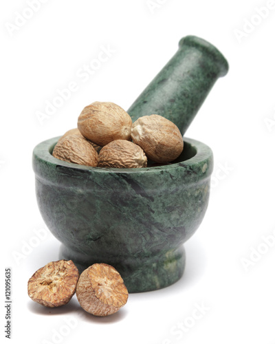 Organic Nutmeg Seed or Jaiphal (Myristica fragrans) on marble pestle and over white background. photo