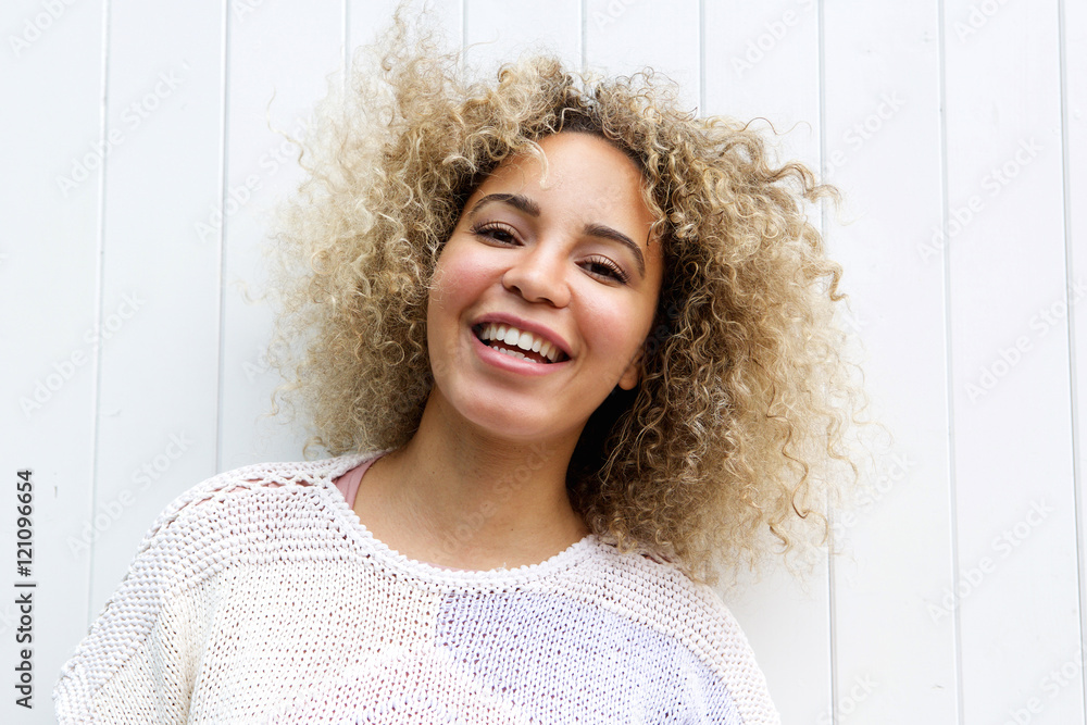 Fototapeta premium Smiling beautiful woman standing by wall