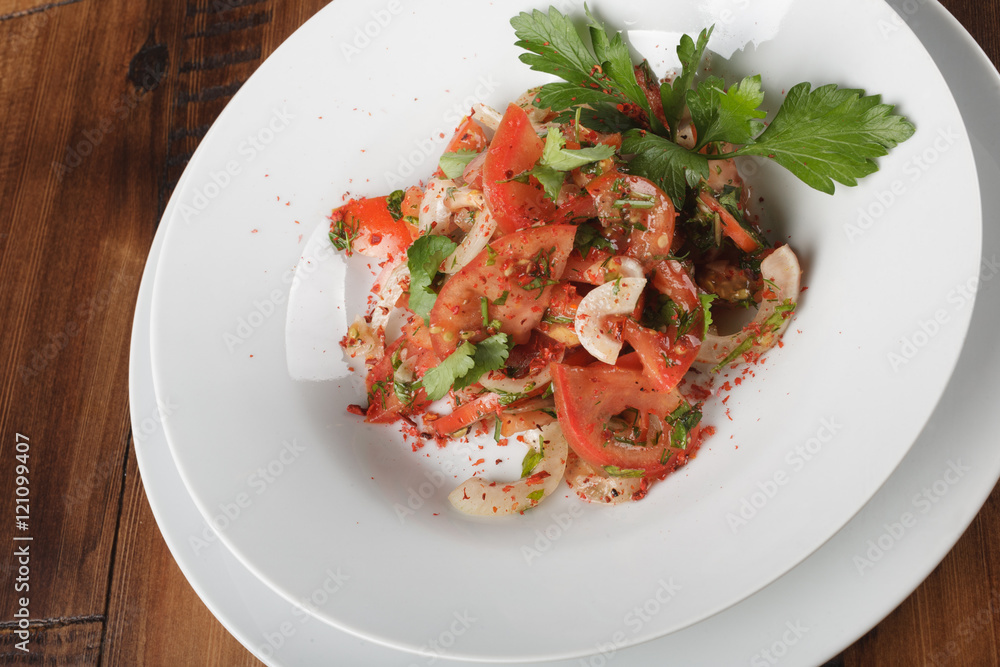 Achichuk - traditional uzbek salad with tomatoes, onions and greens in white plate. wooden background Achichuk - traditional uzbek salad with tomatoes, onions and greens in white plate. wooden background